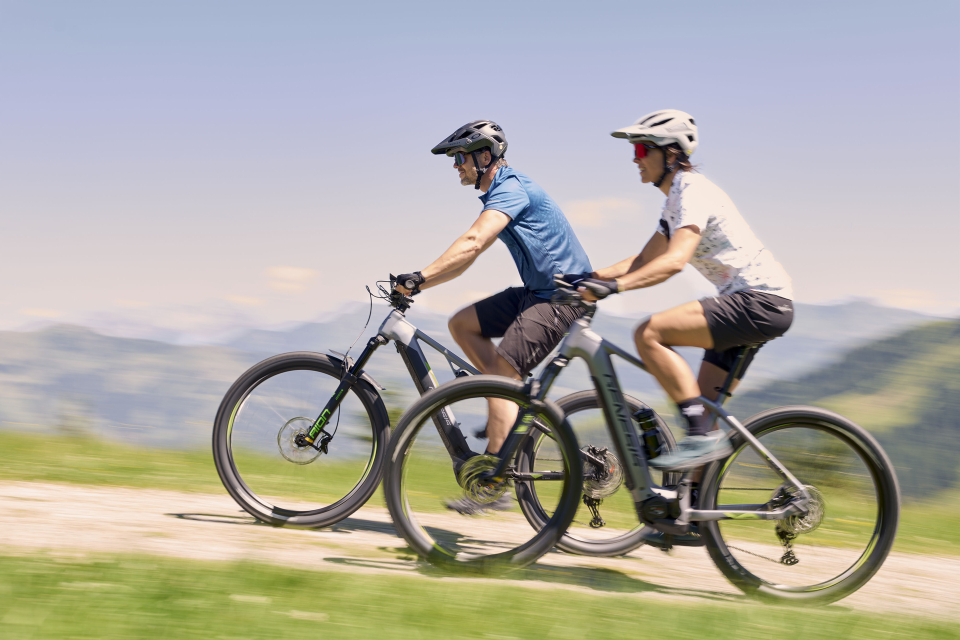 Zwei Biker fahren mit ihrem E-Bike bergauf