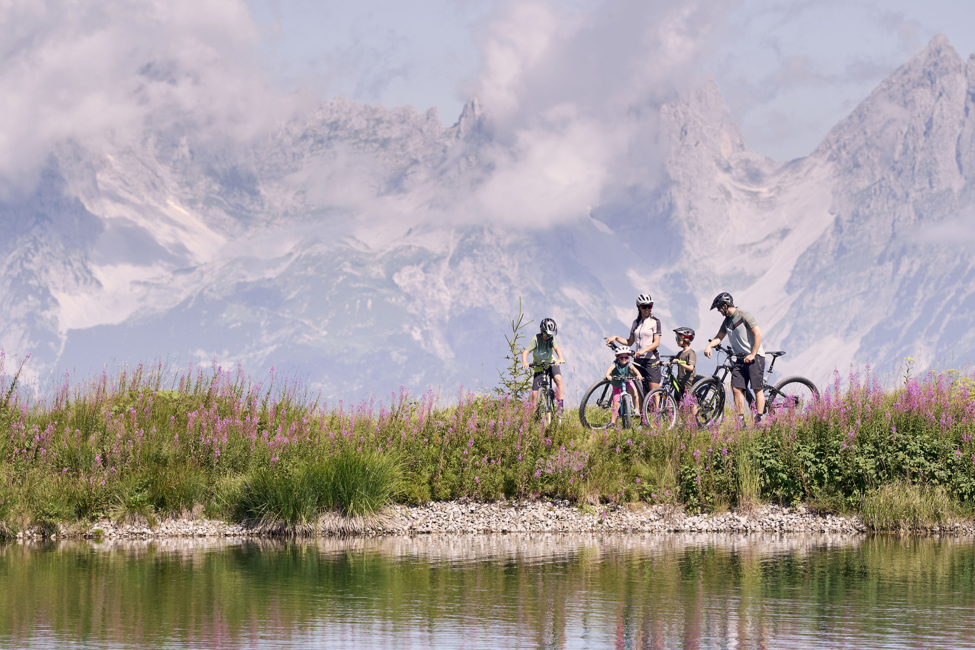 A family stops with their bikes in front of a mountain lake