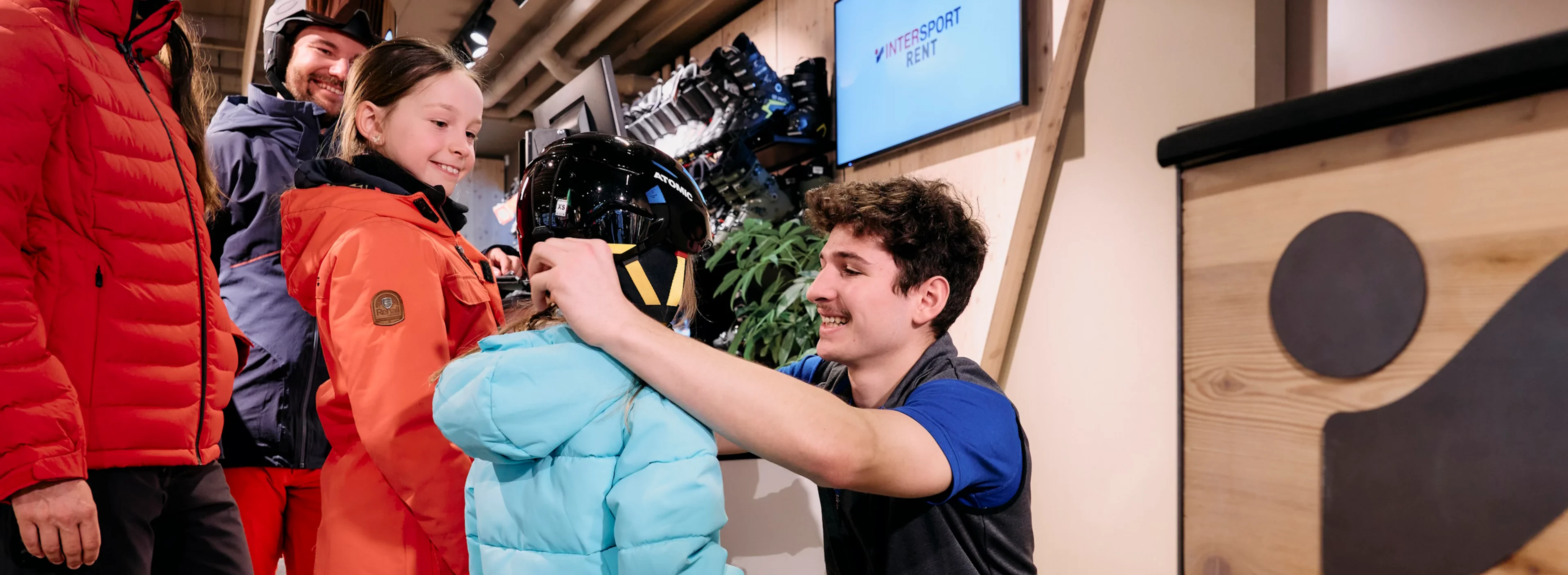 An employee helps a child put on a ski helmet
