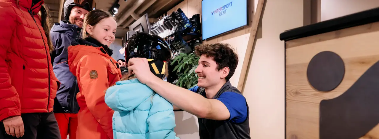 An employee helps a child put on a ski helmet