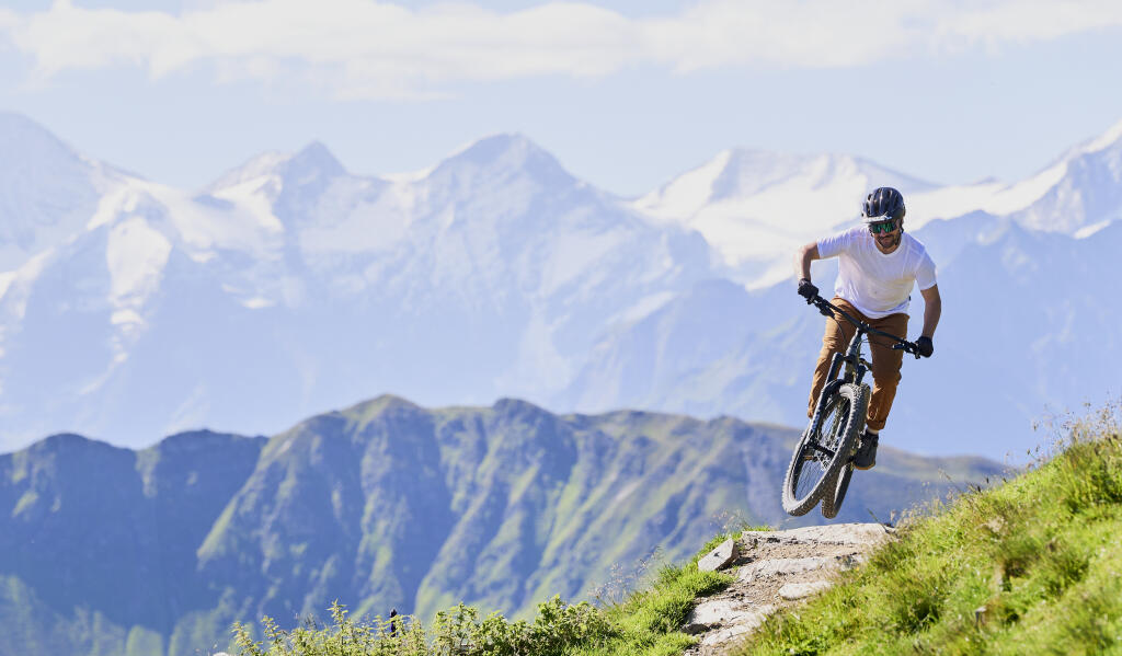 Mann fährt auf einem Bike, im Hintergrund ist die Berglandschaft zu sehen