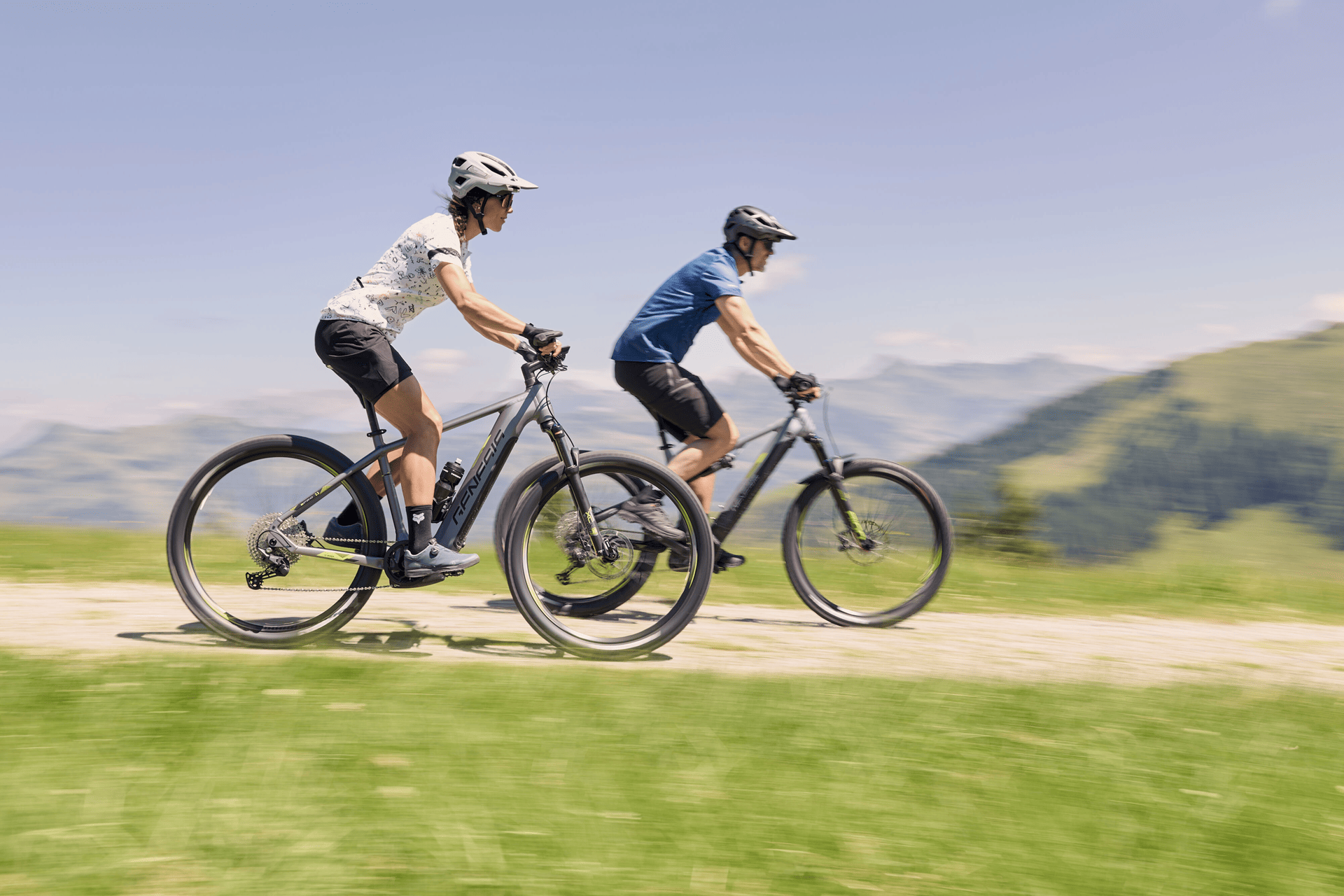 Zwei Radfahrer fahren mit dem E-Bike eine Schotterstraße hinab