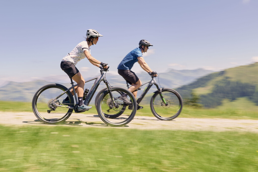 Zwei Radfahrer fahren mit dem E-Bike eine Schotterstraße hinab