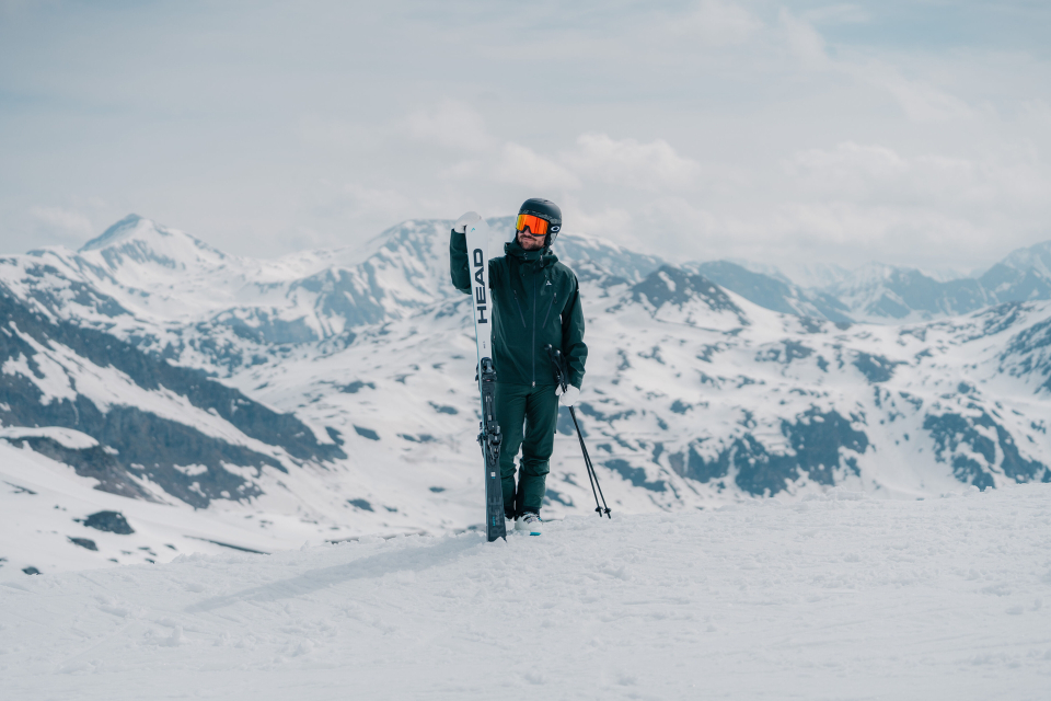 Man steht im Schnee und hält seine Head Ski