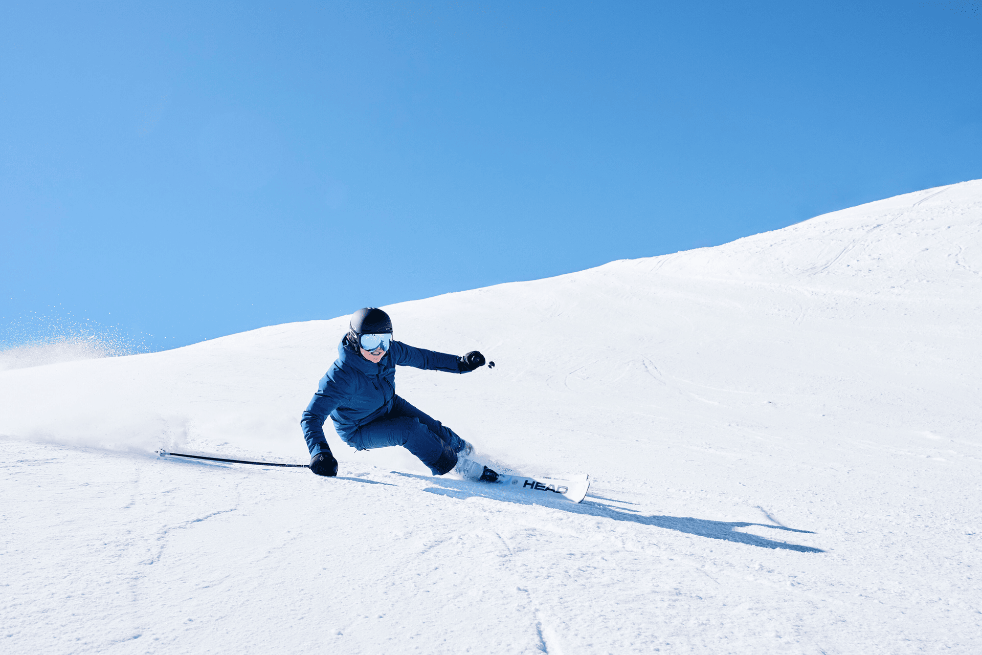 Skifahrer in blauer Kleidung fährt die Piste hinunter